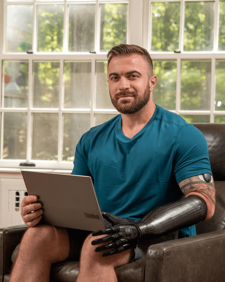 An Eversense CGM device user explains the benefits of the transmitter while sitting in a chair